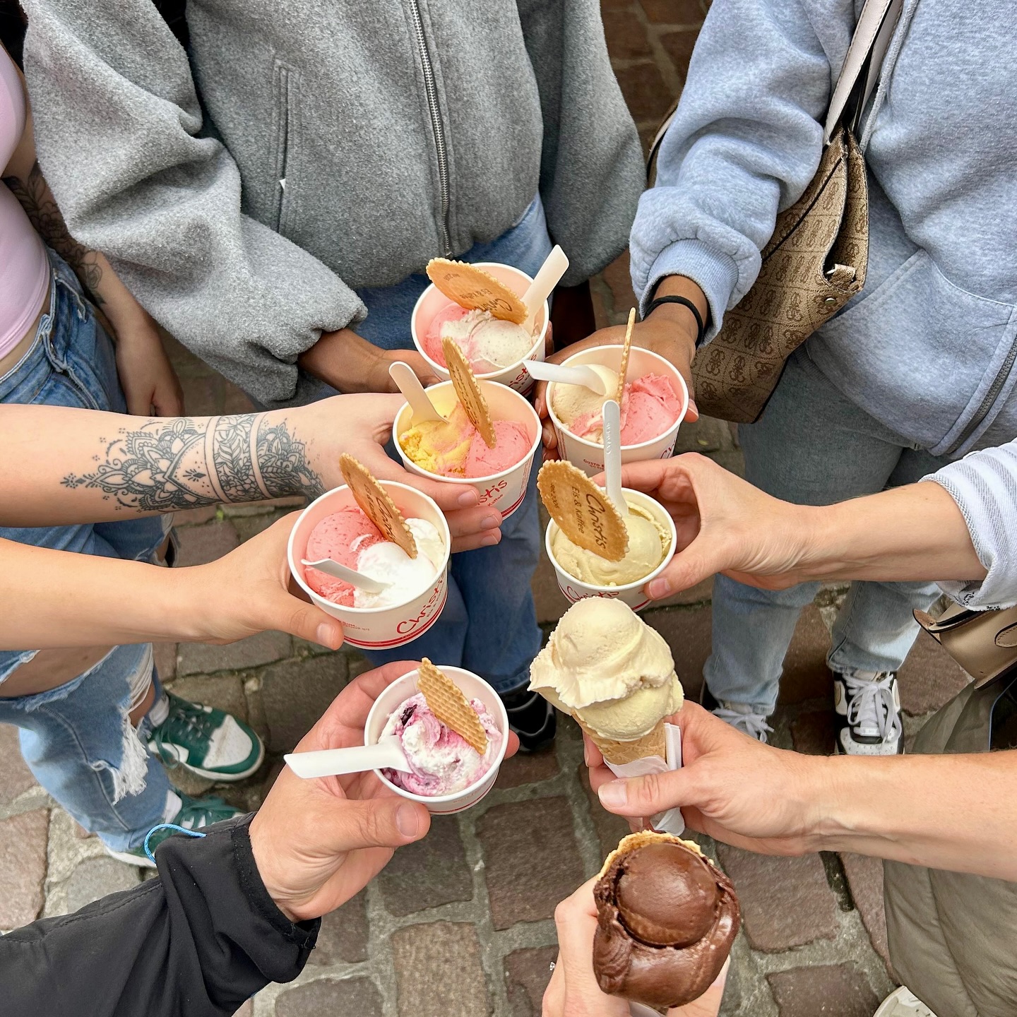 Mitarbeiter stehen in einem Kreis und halten jeweils einen Eisbecher in die Mitte.