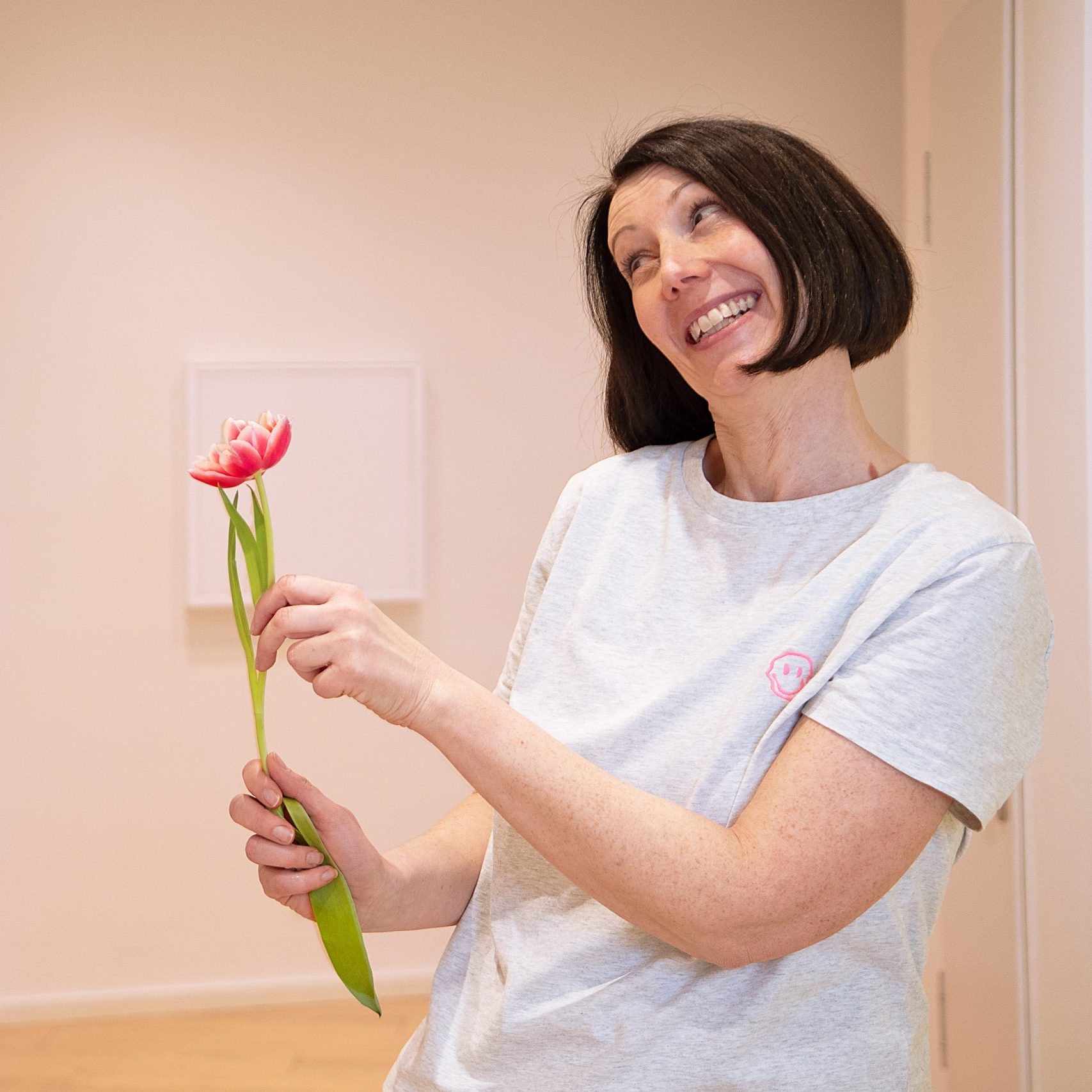 Mitarbeiterin der Praxis für Kieferorthopädie hält eine schöne Blume in der Hand und zeigt diese einer Kollegin 